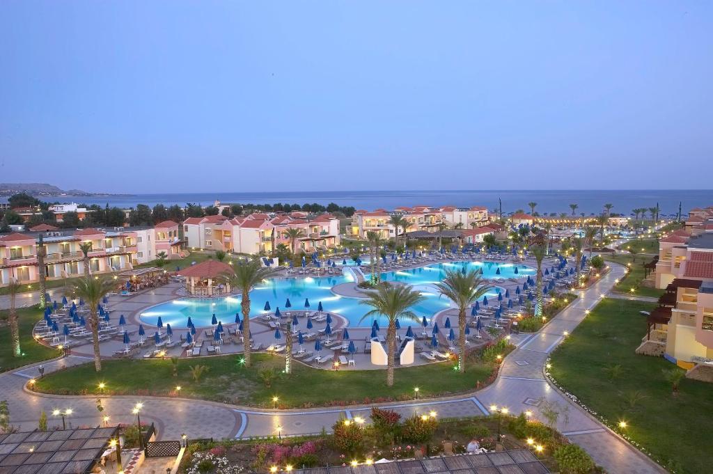 Lindos Princess Beach Hotel baseins piekrastē ar palmām un sauļošanās krēsliem