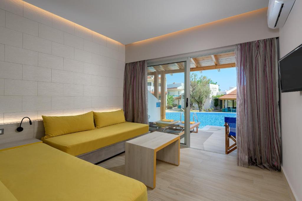 Mūsdienīgs numurs ar dzeltenām mēbelēm un skatu uz baseinu, Lydia Maris Resort & Spa.