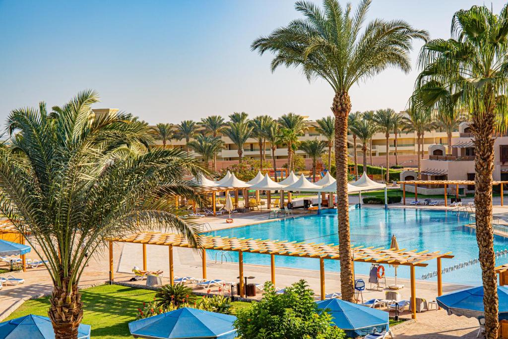 Continental Hotel Hurghada baseins ar palmām un saulessargiem