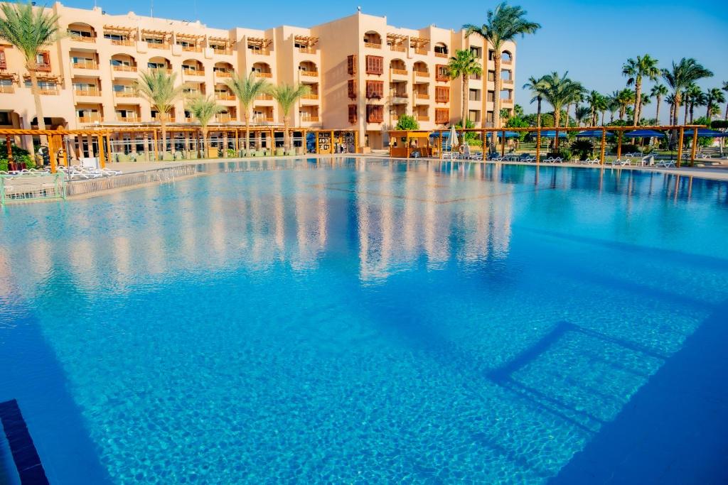 Liels peldbaseins pie Continental Hotel Hurghada ar palmām un viesnīcu fona