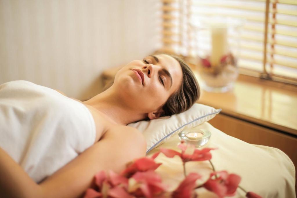 Sieviete guļ spa procedūrā Lydia Maris Resort & Spa, apņemta ar ziediem.