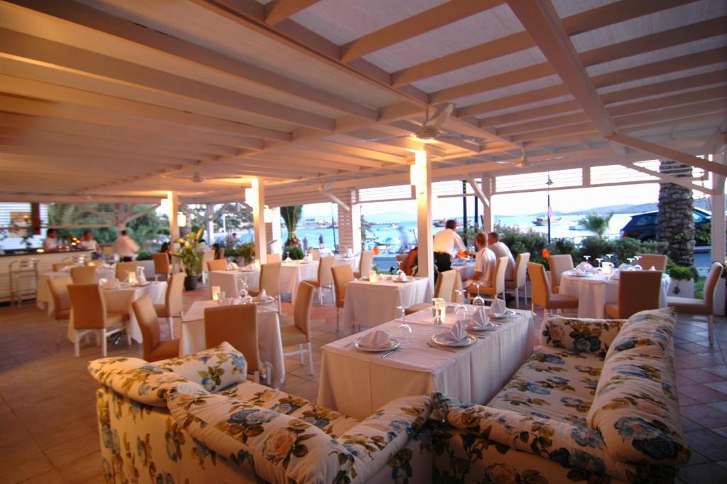 Restorāns pie Diamond of Bodrum Hotel ar elegantiem galdiem un skatu uz piekrasti.