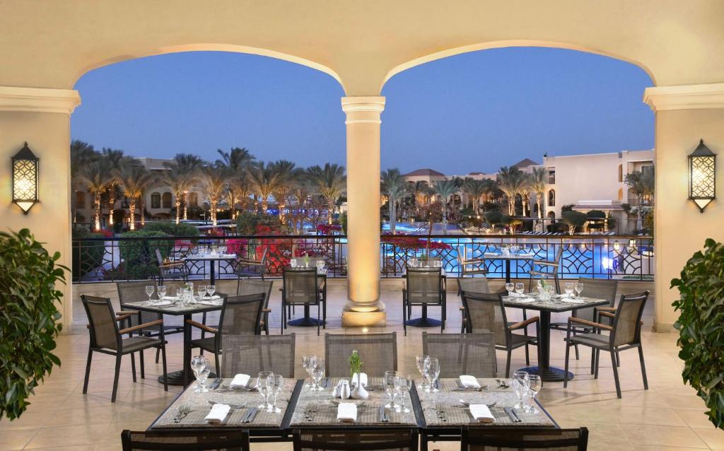 Restorāns ar terasi pie Jaz Aquamarine Resort, skats uz baseinu un palmu alejām.