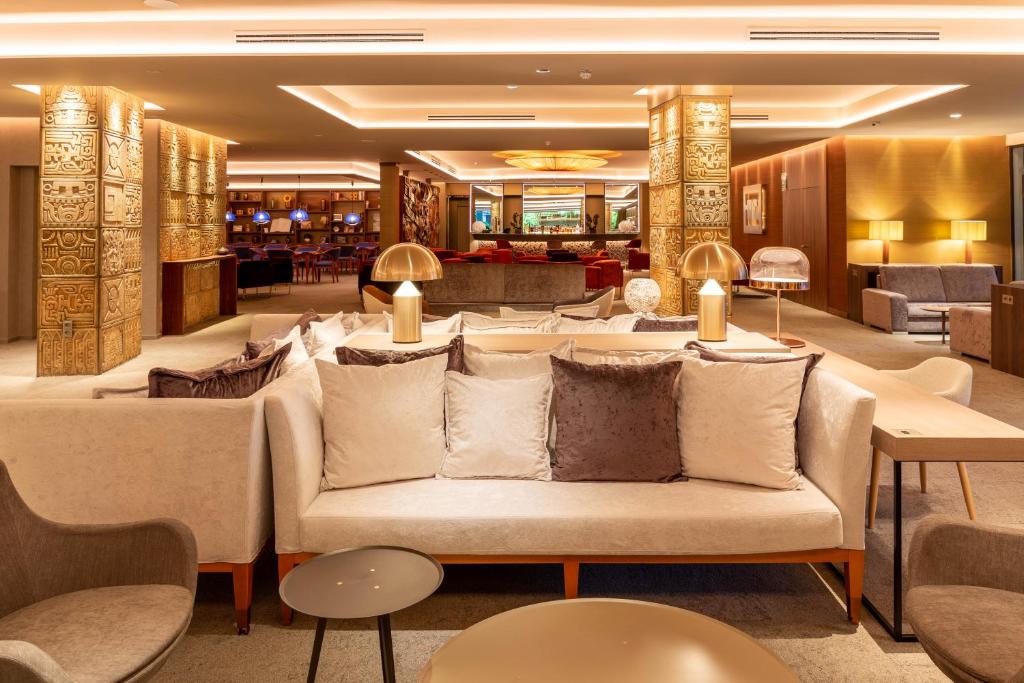 Mūsdienīgs viesnīcas interjers ar elegantām mēbelēm, apgaismojumu un dekoratīvām sienām, radot greznu atmosfēru.