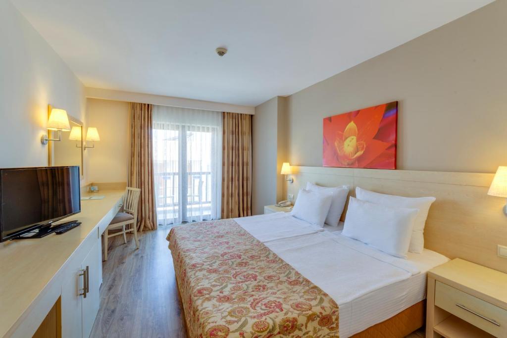 Moderns numurs ar divām gultām Diamond of Bodrum Hotel, ar balkonu un televizoru.