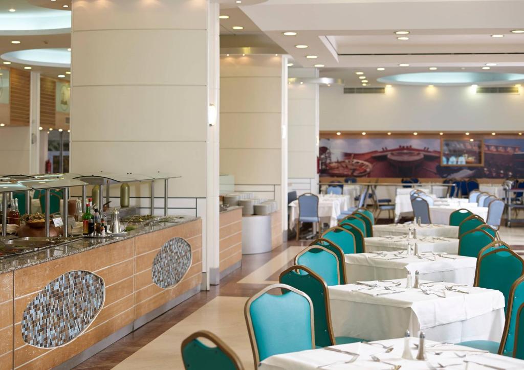 Restorāna interjers ar baltām galdautām un zilo krēslu rindu pie Esperides Beach.