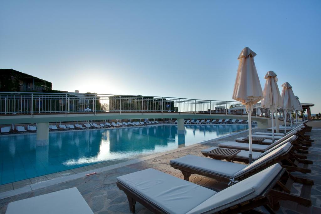Baseins pie Bella Beach Hotel ar sauļošanās krēsliem un lietussargiem