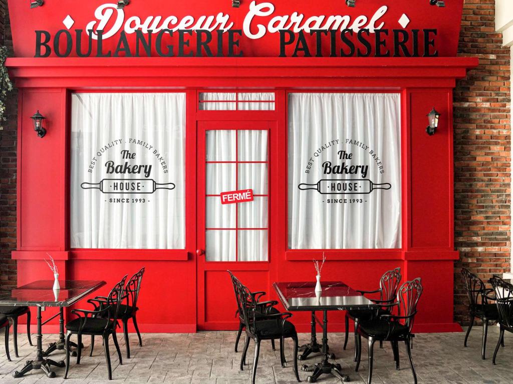 Sarkana kafejnīca Douceur Caramel ar galdiem un krēsliem pie The Bakery House
