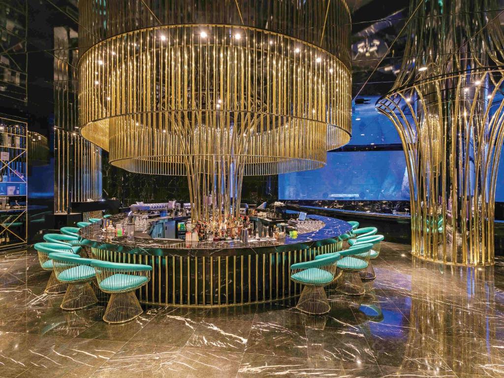 Elegants bārs ar zeltainām lampām un stilīgām krēslām viesnīcā The Land of Legends Kingdom Hotel.