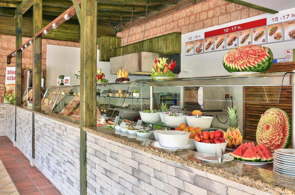 Restorāna bufete ar dažādiem augļiem un dārzeņiem, tostarp dekoratīvām arbūzu kompozīcijām. Interjers ar koka elementiem un akmens apdari rada patīkamu atmosfēru.