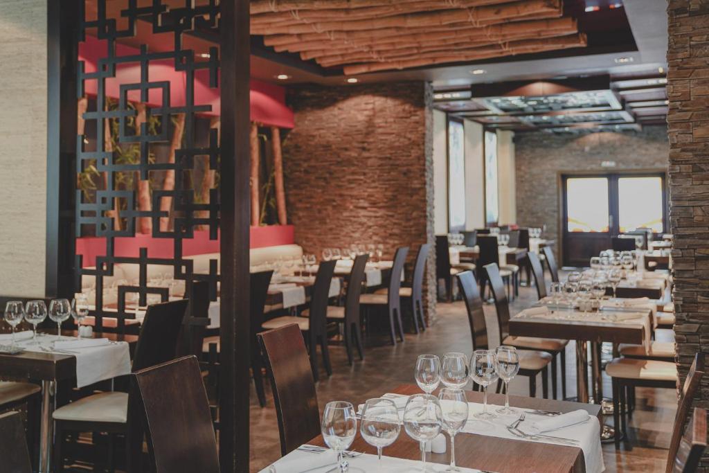 Mūsdienīgs restorāna interjers ar stilīgu apgaismojumu, elegantiem galdiem un krēsliem, kā arī dekoratīvām akmens un koka detaļām.