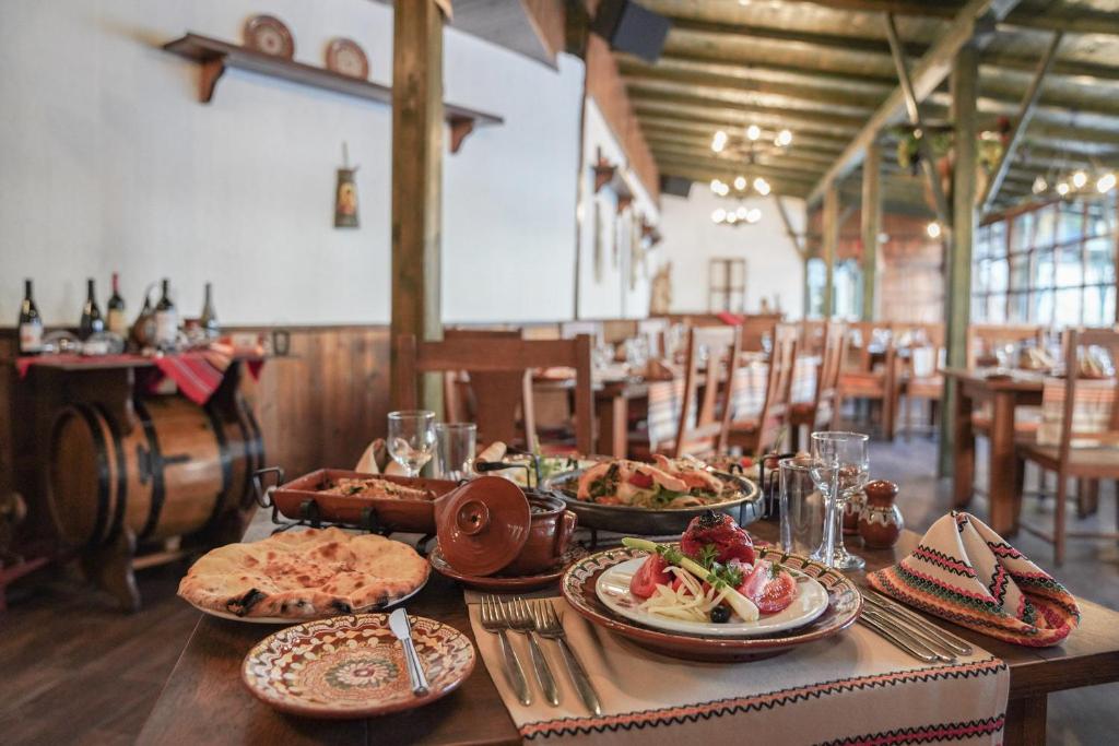 Restorāna interjers ar tradicionāliem ēdieniem uz galda, kas ietver salātus, maizi un dzērienus. Rūpīgi noformēts galds ar dekoratīvām šķīvju un galda piederumiem.