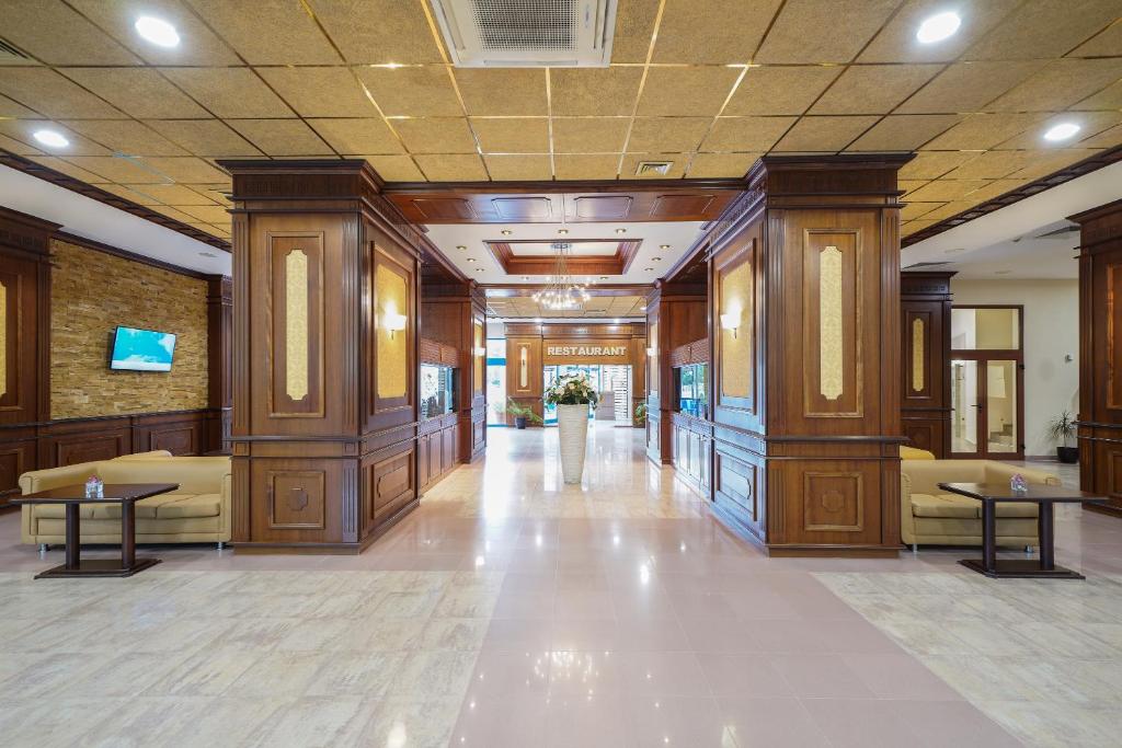 Elegants restorāna interjers ar koka apdari, gaišām flīzēm un komfortablām sēdvietām. Gaismas ķermeņi piešķir siltu atmosfēru, radot aicinošu vidi.