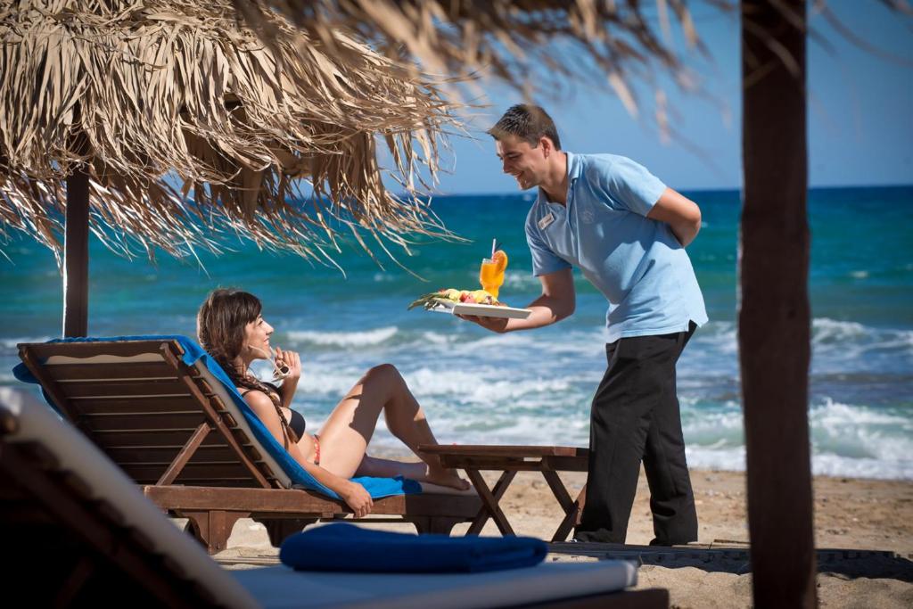 Bella Beach Hotel viesmīlis pasniedz dzērienu un uzkodas pludmalē