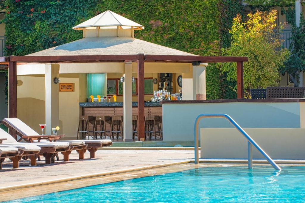 Bella Beach Hotel baseins ar bāru un saulē piepildītiem krēsliem