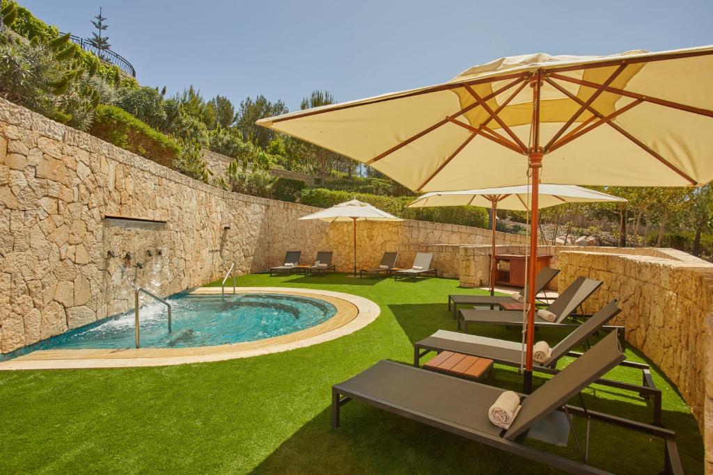 Tāpat kā atpūtas zona ar saules gultām, saulessargiem un nelielu baseinu, kas ieskauts akmens sienā un zaļajā zālē.