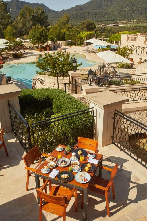 Luksusa brokastis pie galda ar dažādiem ēdieniem un dzērieniem, skats uz peldbaseinu un kalnu ainavu.