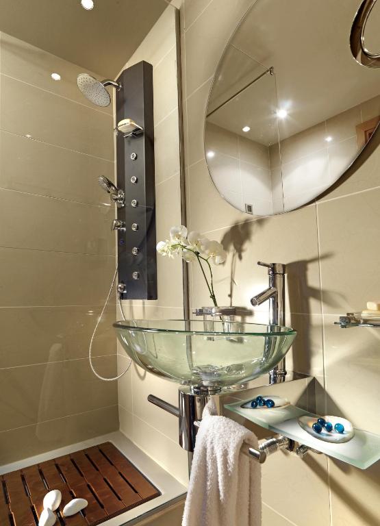 Mūsdienīga vannas istaba ar stikla izlietni un dušas kabīni.