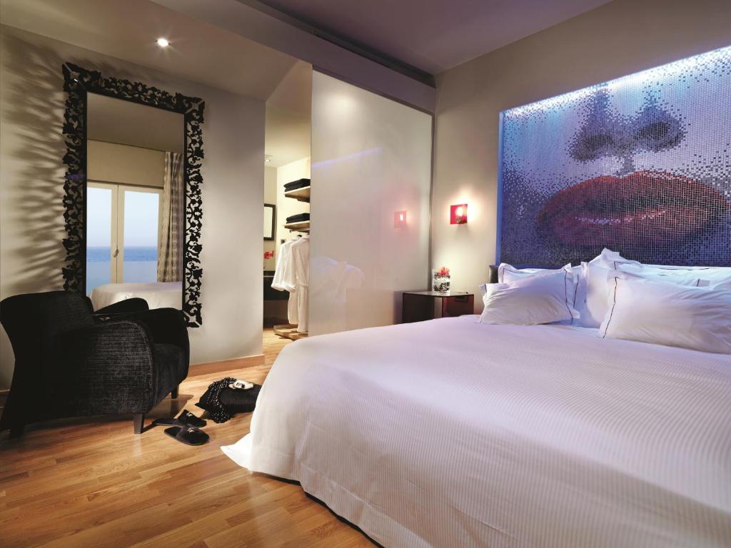 Mūsdienīgs viesnīcas numurs ar māksliniecisku sienu un skatu uz jūru.