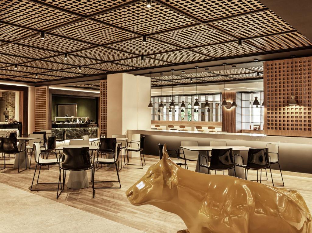 Mūsdienīgs restorāns viesnīcā Esperides Beach ar elegantu interjeru un zelta govs figūru.