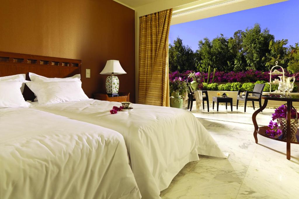 Gultas numurs ar balkonu un ziediem, gaiša apdare un dabiska gaisma.