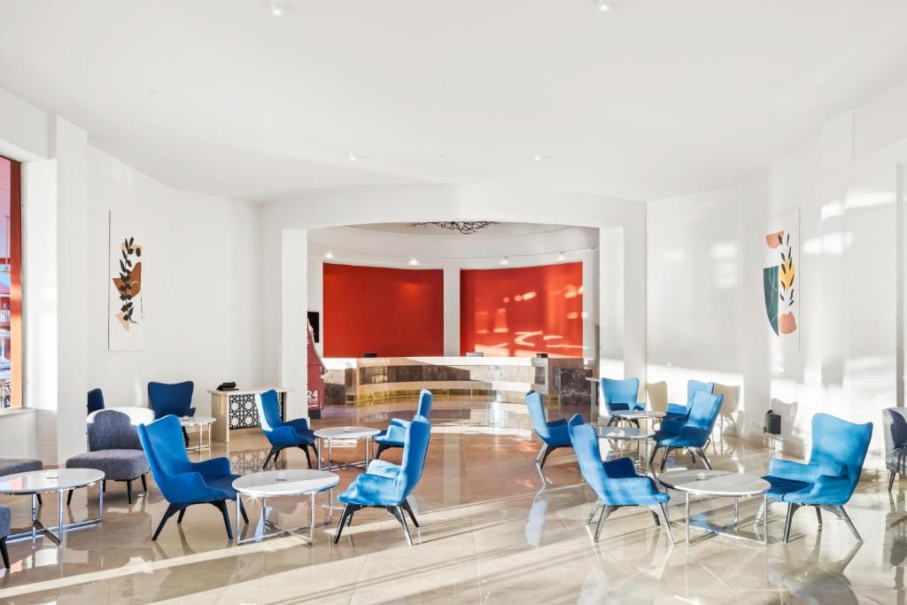 Mūsdienīga uzgaidāmā zona ar zilu krēslu un stikla galdiem, Pickalbatros Laguna Club Resort.