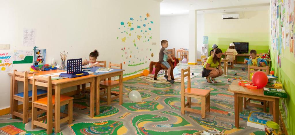 Bērnu rotaļu istaba Xperience Sea Breeze Resort ar galdiem un rotaļlietām.
