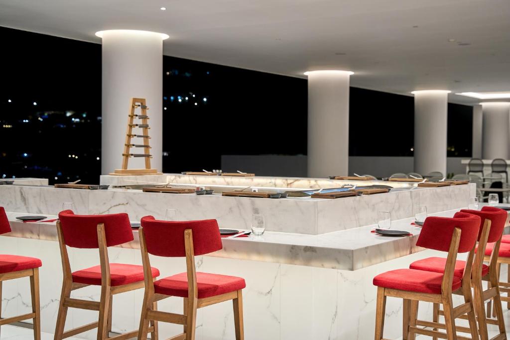 Lindos Grand Resort & Spa bārs ar sarkanām krēsliem un marmora letes.