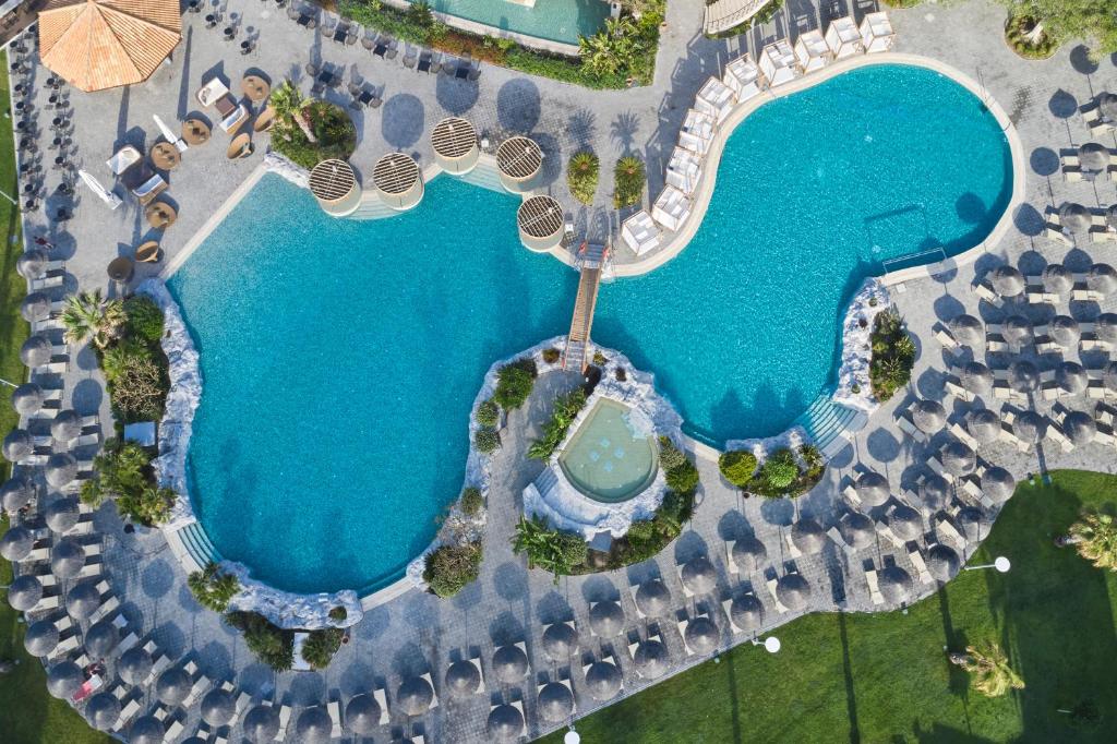 Atlantica Imperial Resort baseins ar sauļošanās gultām un tropisku apzaļumošanu