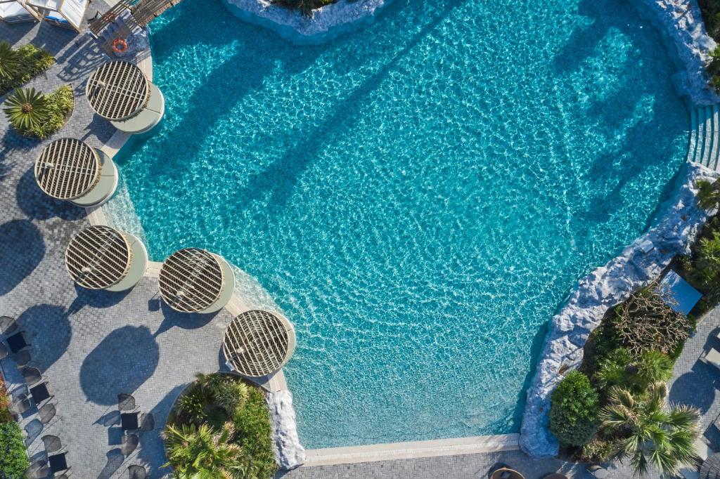 Atlantica Imperial Resort baseins ar saulainām terasēm un palmām