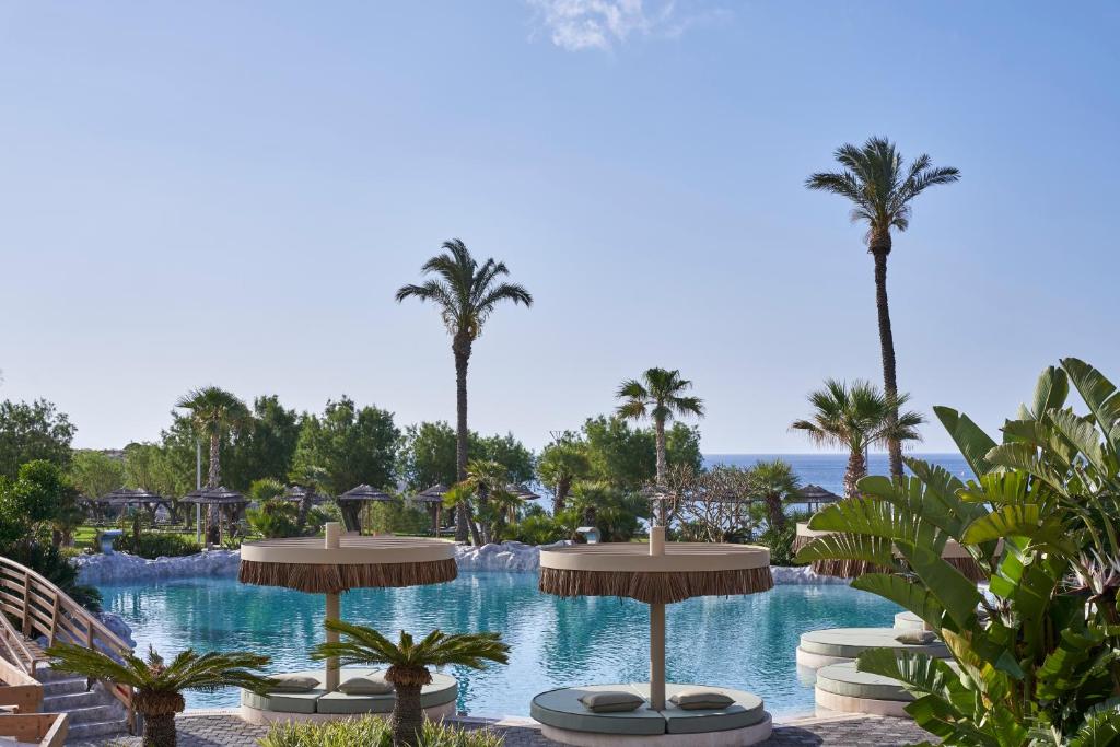 Atlantica Imperial Resort peldbaseins ar palmiem un saulessargiem piekrastē
