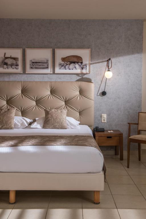 Elegants numurs Bella Beach Hotel ar ērtiem gultas piederumiem un mākslas darbiem uz sienas.