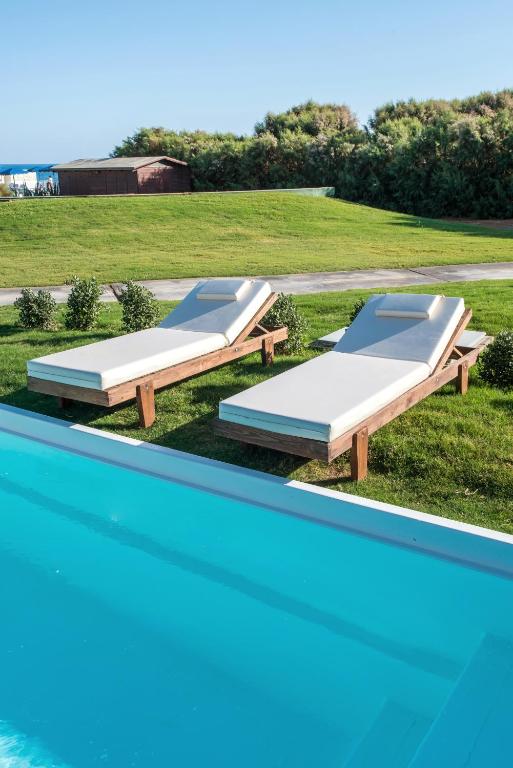 Peldbaseins un sauļošanās krēsli pie Bella Beach Hotel