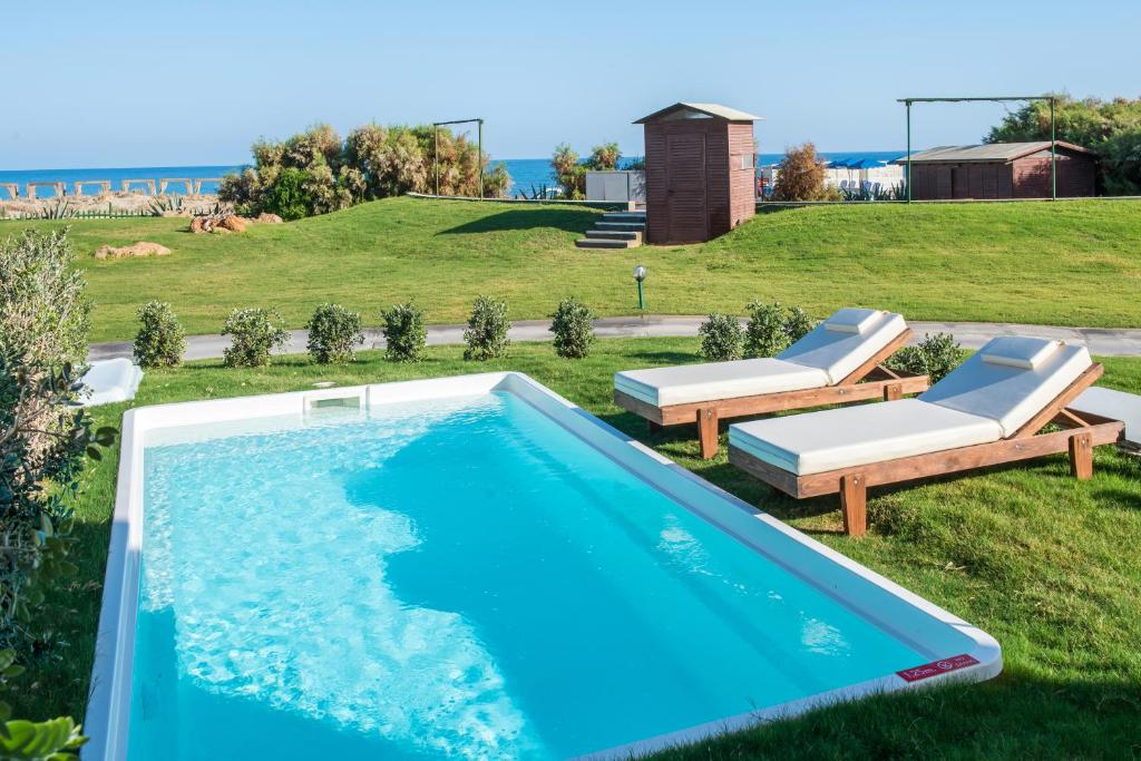 Bella Beach Hotel baseins piekrastē ar sauļošanās krēsliem.
