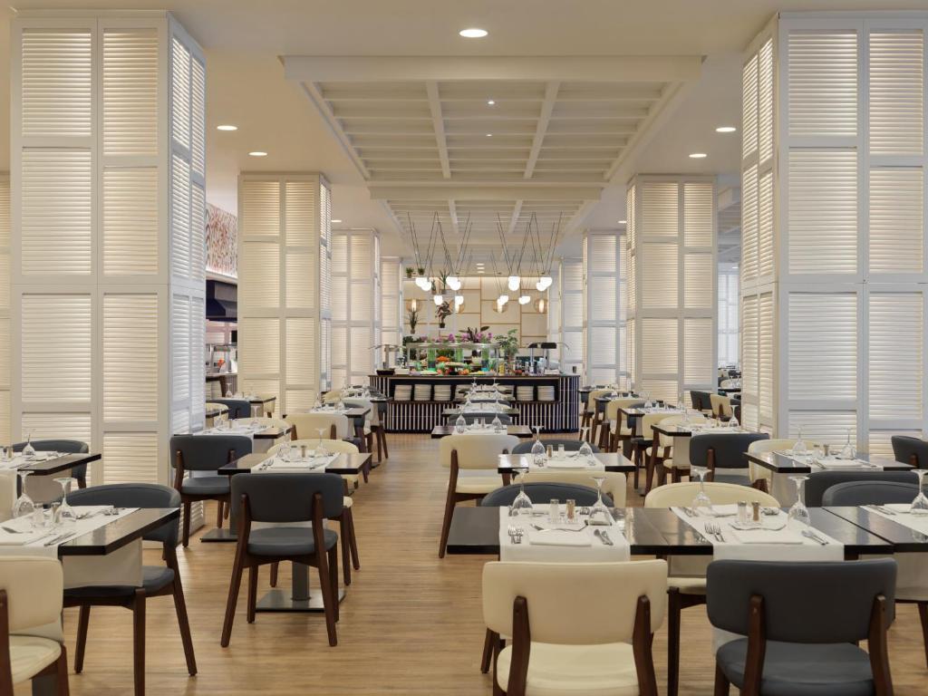 Moderns restorāns ar elegantiem galdiem un krēsliem, plaša telpa ar gaismas elementiem un dekoratīvām rūts sienām. Ideāla vieta relaksējošai maltītei.