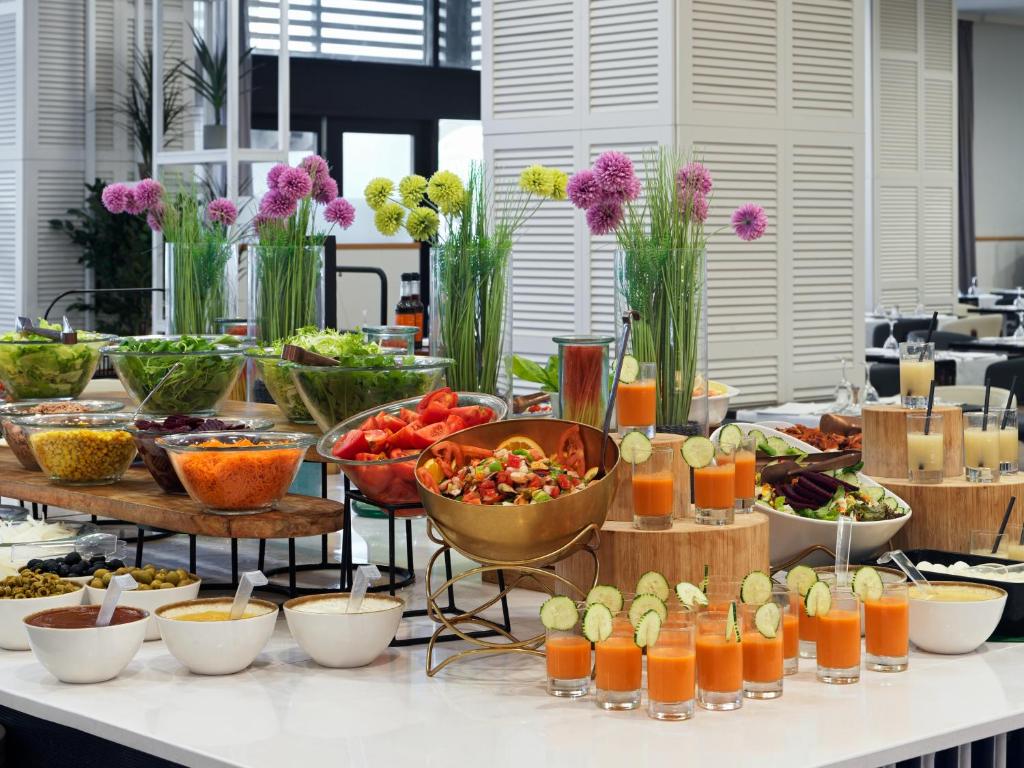 Bagātīgs bufetes galds ar dažādām salātiem, dārzeņiem un dzērieniem, dekorēts ar ziediem. Ideāls veselīgas ēšanas iedvesmas avots.