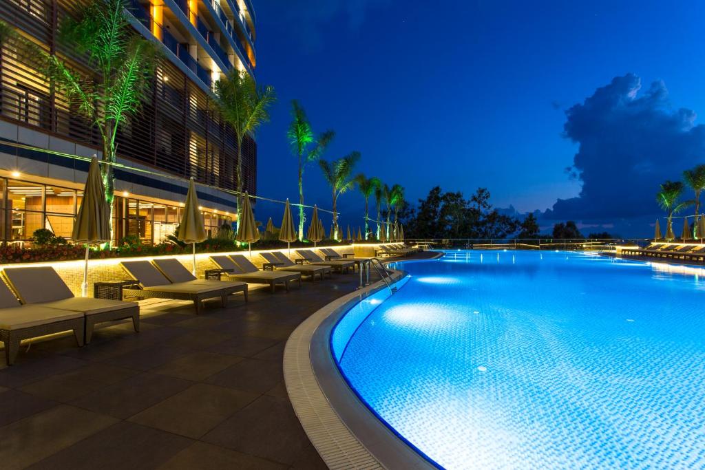 Michell Hotel & Spa baseins ar palmām piekrastē naktī.