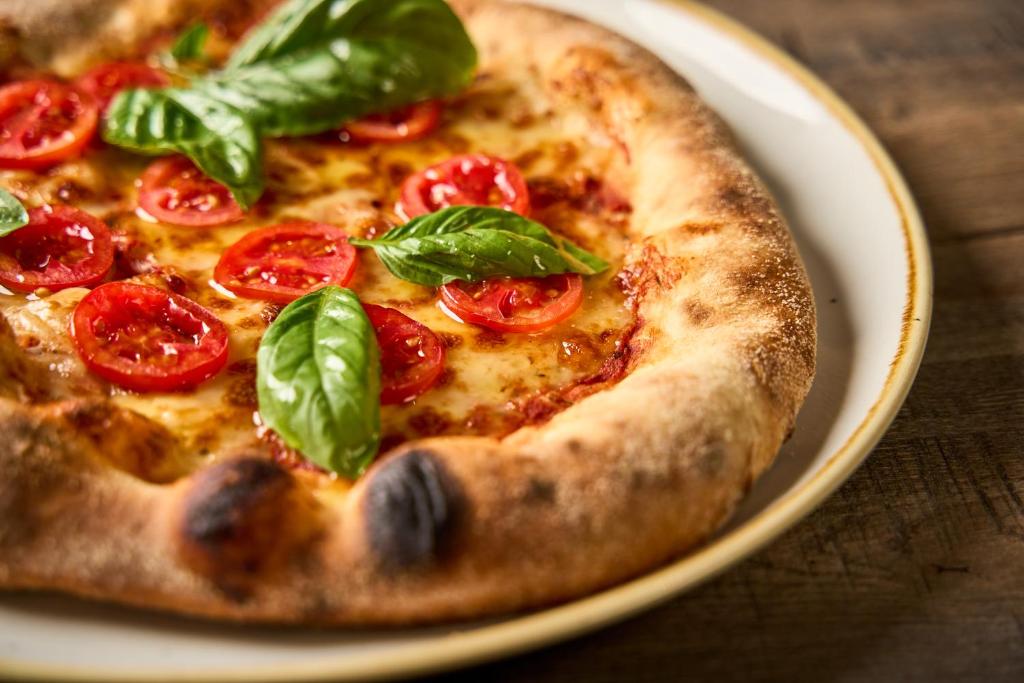 Gardēžu pica ar tomātiem un baziliku uz šķīvja.