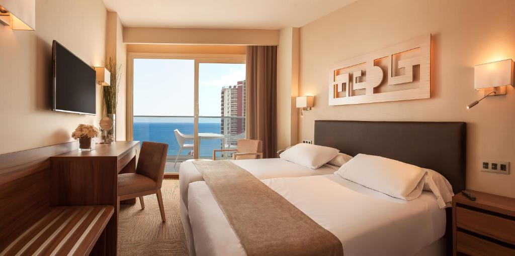 Mūsdienīga viesnīcas numura iekārtojums ar divām gultām, koka mēbelēm un plašu logu, no kura paveras skats uz jūru. Numurā ir televizors, naktslampas un neliela ēdamzona.