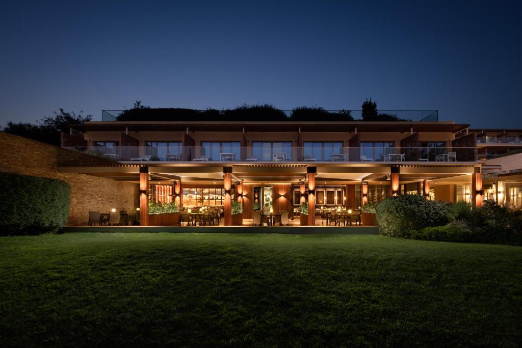 EPIC SANA Algarve Hotel fasāde naktī ar silti apgaismotu restorāna terasi un numuru balkoniem.