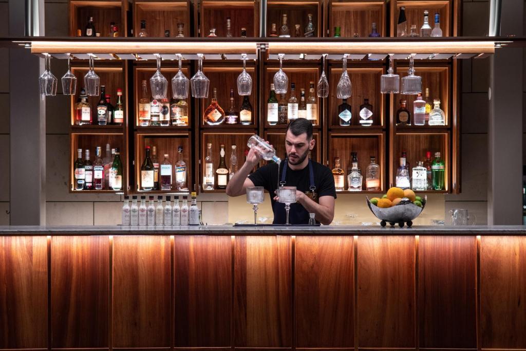 Bārmenis gatavo kokteili EPIC SANA Algarve Hotel bārā ar plašu dzērienu izvēli fonā