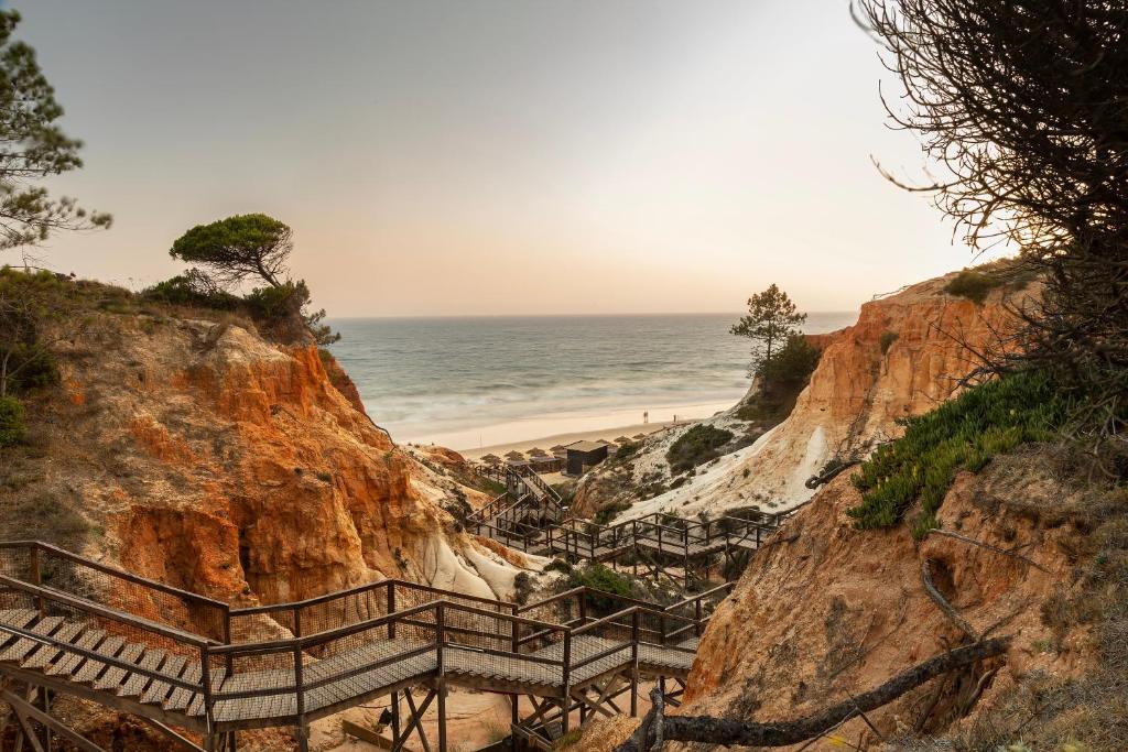 Koka laipa uz pludmali caur sarkanajām klintīm pie EPIC SANA Algarve Hotel.