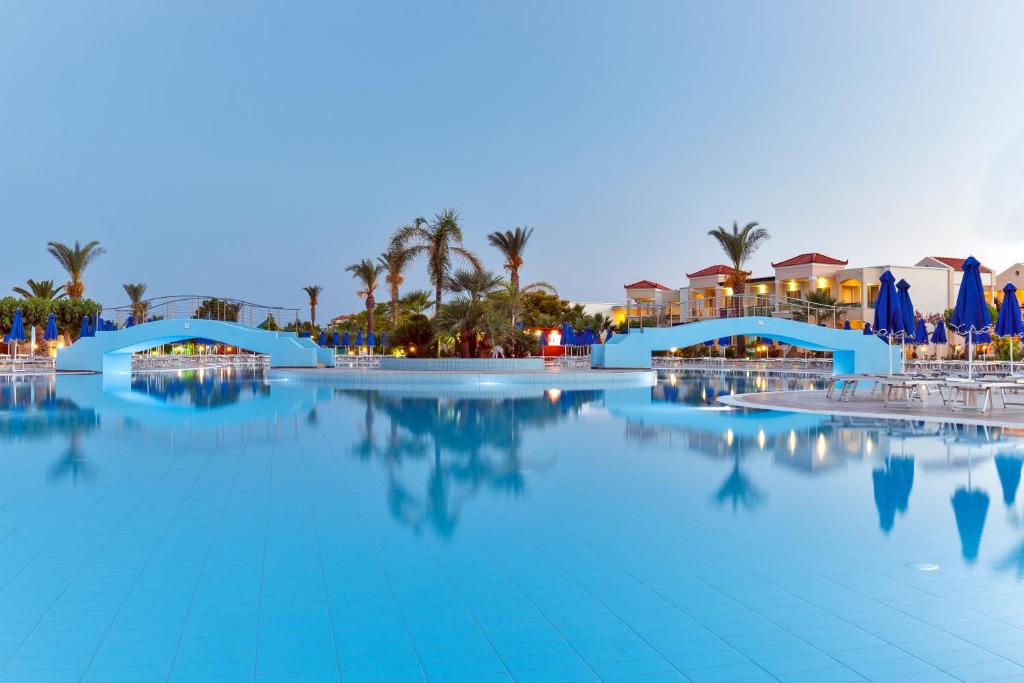 Lindos Princess Beach Hotel baseins ar zilu ūdeni un palmu kokiem