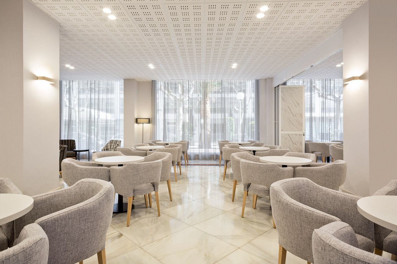 Gaiša atpūtas zona ar ērtiem krēsliem un galdiem viesnīcā Best Da Vinci.