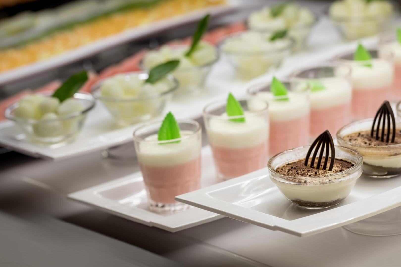 AQUA Hotel Silhouette & Spa restorāna desertu izlase glāzītēs — krēmīgi kārtojumi ar piparmētru un šokolādes dekorācijām bufetes zonā.