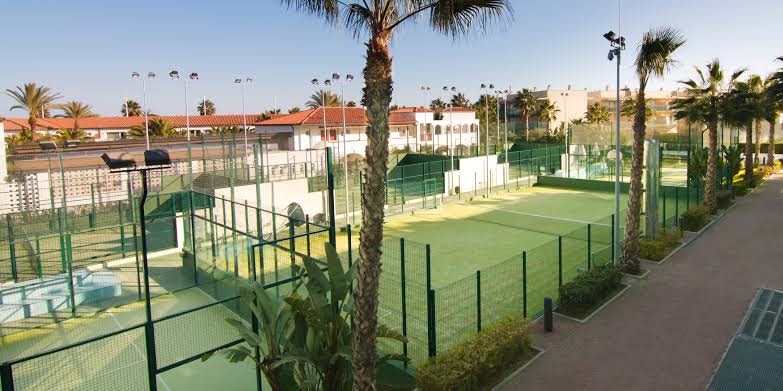 Estival Park Marena sporta komplekss ar vairākiem padela tenisa kortiem, ko ieskauj palmas un viesnīcas ēkas saulainā piekrastes reģionā.