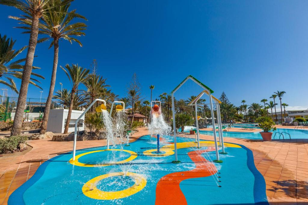 Krāsains ūdens atrakciju parks ar strūklakām un palmām, kas nodrošina izklaidi un atpūtu saulainā dienā. Ideāla vieta ģimenēm un bērniem.