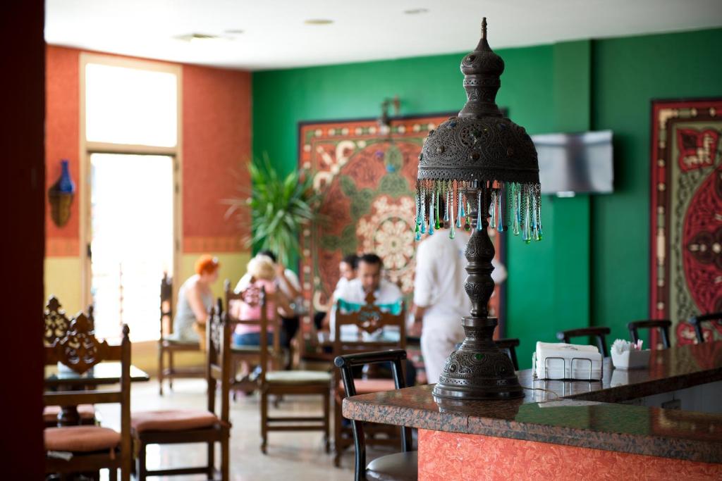 Viesnīcas Amphoras Blu restorāns ar stilīgu lampu un viesiem pie galdiem.