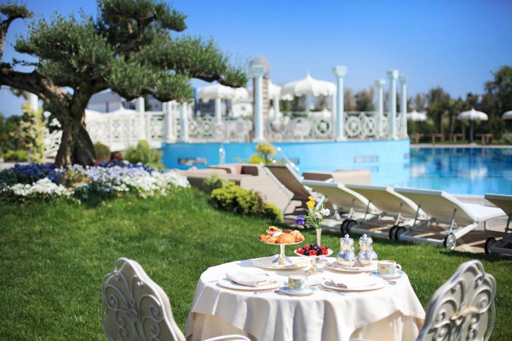 Romantiska brokastis pie galda dārzā, blakus baseinam, ar ziediem un olīvkokiem. Ideāla atpūtas vieta, lai izbaudītu skaisto laiku un gardas uzkodas.