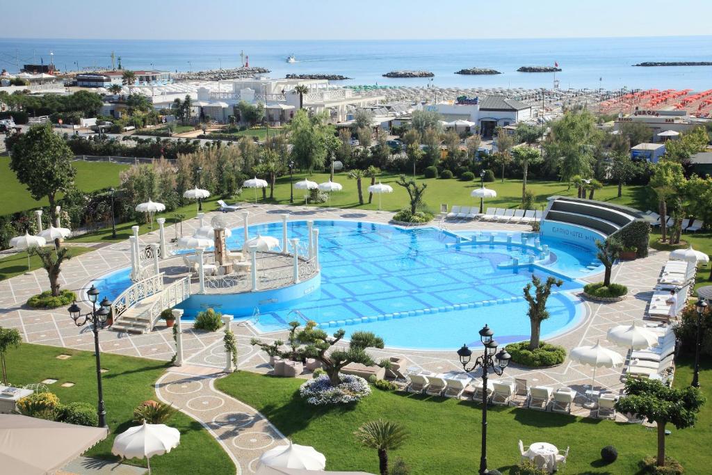 Lieliska atpūtas zona ar plašu baseinu un zaļām zālēm, redzams jūras skats un pludmales krēsli. Ideāla vieta relaksācijai un atpūtai.